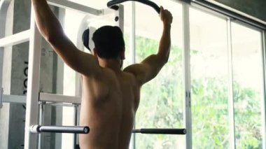 Güçlü adam spor salonunda yatay barda egzersiz yukarı çekin yapıyor