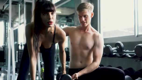 Personal trainer aiuta il suo cliente femminile a fare un braccio manubrio fila esercizio in palestra — Video Stock