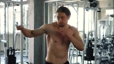 Gömleksiz kaslı adam spor salonunda gölge boks pratik
