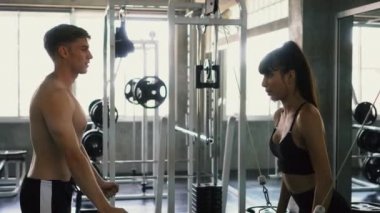 Spor eğitmeni spor salonunda göğüs egzersiz üzerinde kablo çapraz yapıyor onu kadın müşteri rehberlik