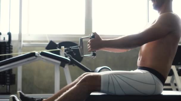 无衬衫肌肉男子在健身房的机器上做坐电缆行练习 — 图库视频影像