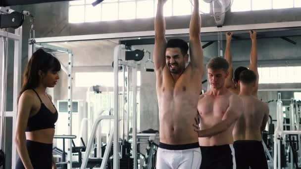 Przyjaciele doping człowiek praktykujący podbródek UPS ćwiczenia na barach na siłowni — Wideo stockowe