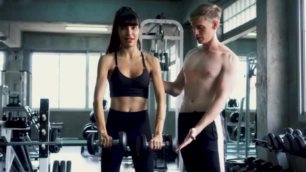 Sportswoman practicing front lateral raise exercise with her trainer at the gym — Stock Video