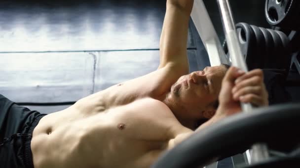 Без сорочки м'язистий чоловік робить барбелл лавка прес вправи в спортзалі — стокове відео