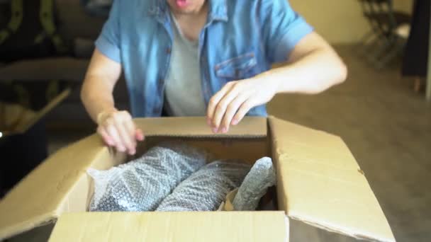 Förvånad asiatisk man Unboxing paket hemma — Stockvideo
