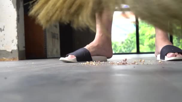 Human legs wearing slippers using sweeping broom inside the house — Stock Video