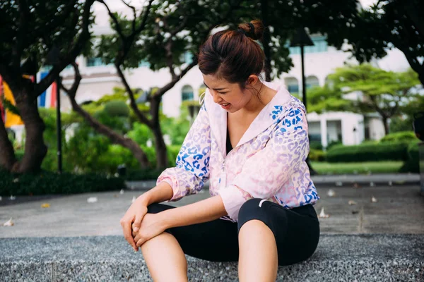 Молодая азиатка, страдающая от боли в коленном суставе на пробежке — стоковое фото