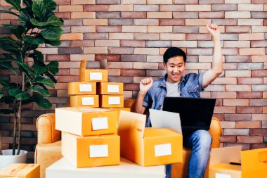 Heyecan ile evde kutular paketleri ile laptop kullanarak erkek iş girişimci
