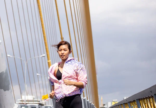 Азиатская спортсменка бегает по городскому мосту — стоковое фото