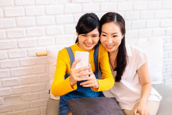 Счастливая азиатская дочь-подросток и мать среднего возраста делают селфи или видео-звонки — стоковое фото