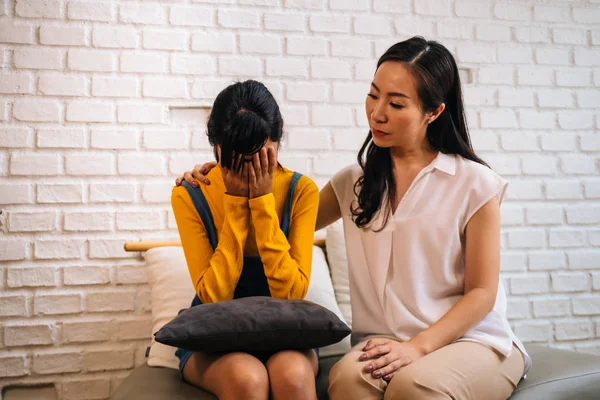 Asian mother comforting crying teenage daughter in miserable, stressed, depressed, sad state of mind — Stock Photo, Image