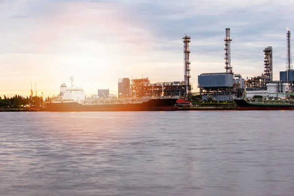 Petroleum oil refinery plant beside river in sunset