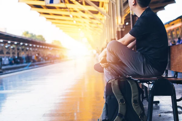 Young Asian male travel backpacker sit and wait for a train in railway platform in Bangkok, Thailand — Stock Photo, Image