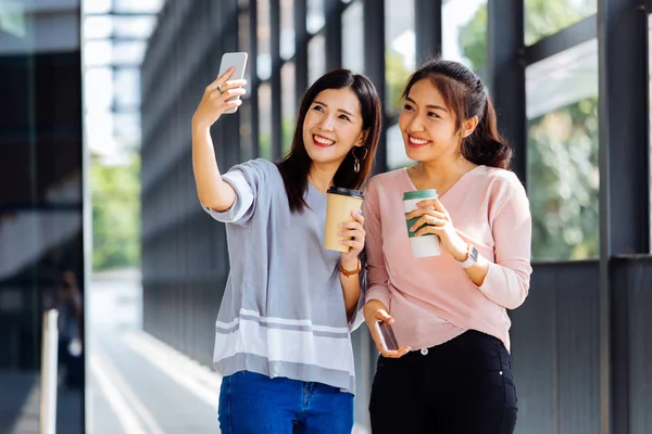 Jóvenes asiáticos tomando fotos selfie juntos dentro del edificio de vidrio — Foto de Stock