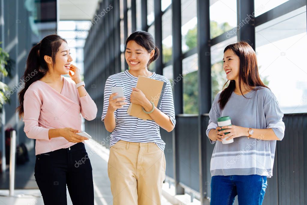 Young Asian business women talking while walking in office building in casual wear