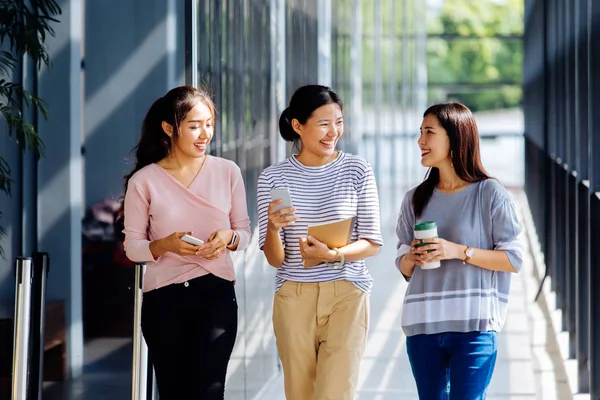 Jóvenes mujeres de negocios asiáticas hablando mientras caminan en el edificio de oficinas en ropa casual — Foto de Stock