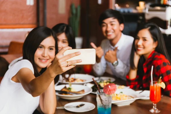 Grupo de amigos masculinos y femeninos asiáticos felices tomar foto selfie y hacer un brindis social en el restaurante —  Fotos de Stock