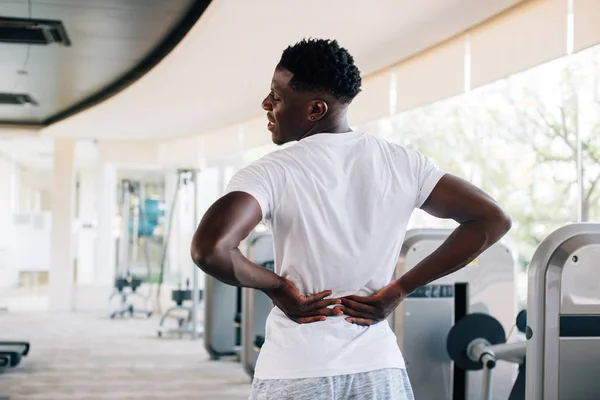 Sportive man touching painful lower back