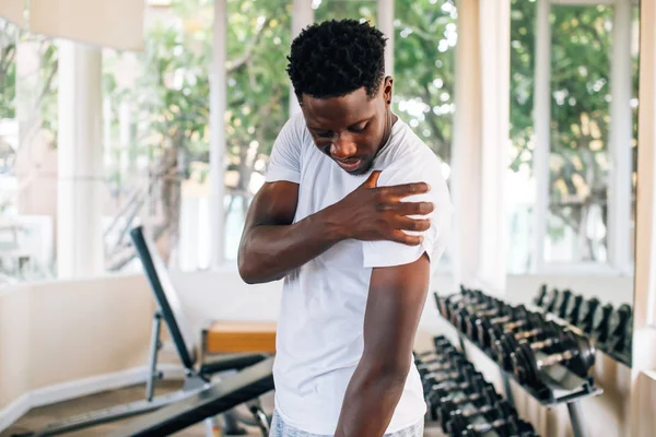 Sportsman holding painful shoulder in gym — Stock Photo, Image