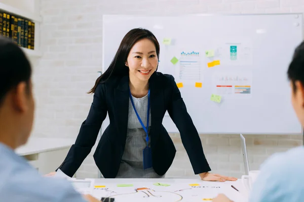 Asiática madura mujer de negocios sonriendo y discutiendo con otros hombres de negocios — Foto de Stock
