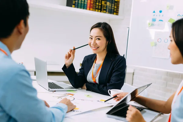 Asiatische reife Geschäftsfrau lächelt und schaut in die Kamera, während sie in einem Meeting sitzt — Stockfoto