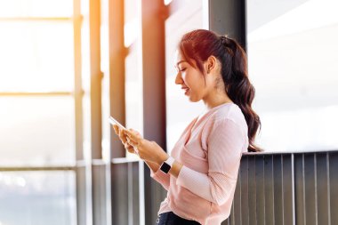 Asyalı kadın kolu ve sörf akıllı telefon eğilerek