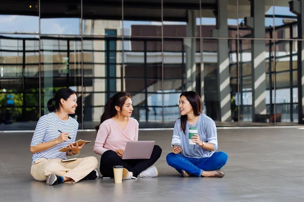 Gruppo di studenti asiatici che studiano su laptop seduti sul pavimento — Foto Stock