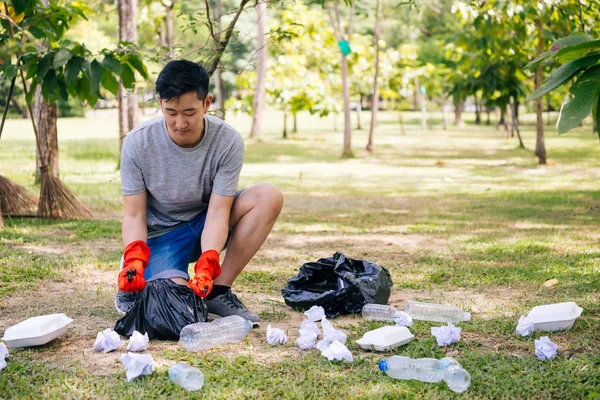 Jonge man het verzamelen van vuilnis in vuilniszak in het Park — Stockfoto
