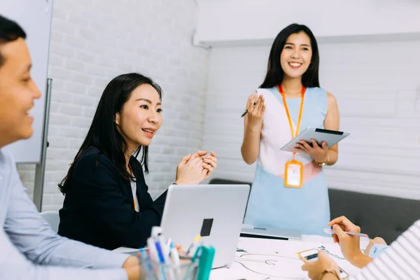 Asiatische reife Geschäftsfrau diskutiert und spricht mit anderen Geschäftsleuten, während sie in einem Meeting zusammen mit persönlichen Assistenten sitzt — Stockfoto