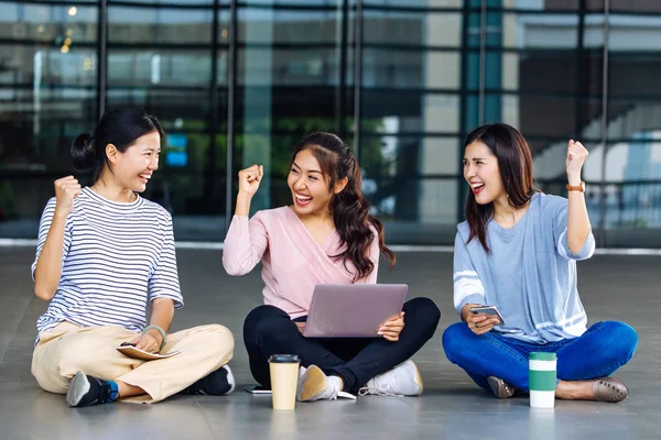 Азиатские студенты сидят на полу и показывают кулак — стоковое фото