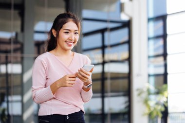 Asyalı kadın gülümseyen ve akıllı telefon tutan