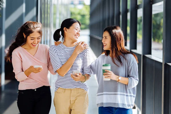 Retrato de tres mujeres hermosas jóvenes hablando en el pasillo del edificio de cristal — Foto de Stock