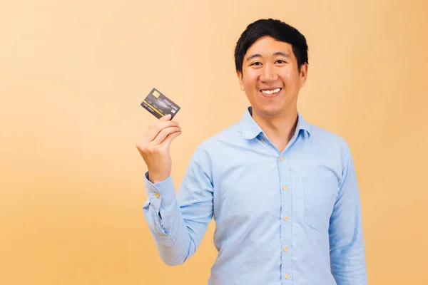 Młody szczęśliwy azjatycki człowiek trzyma kartę kredytową — Zdjęcie stockowe