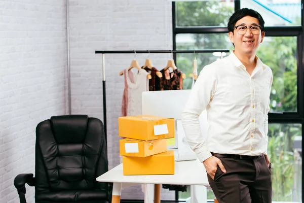 Joven empresario asiático sonriente con gafas de pie y posando en la oficina — Foto de Stock