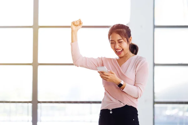 Азиатская женщина радуется после получения новостей по телефону — стоковое фото