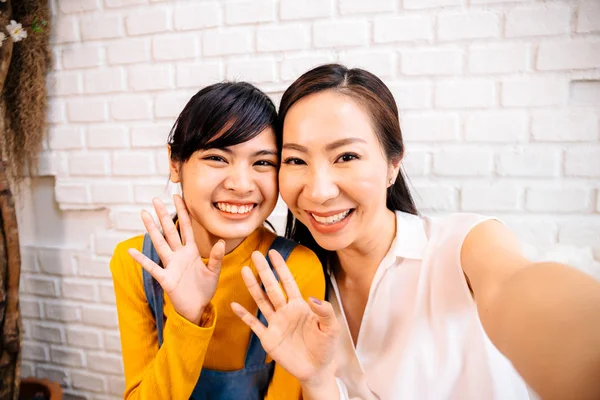 Happy Asian teenage daughter and middle-aged mother taking selfie or video calling — Stock Photo, Image