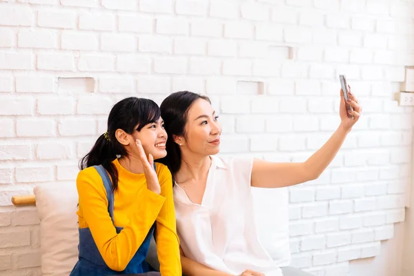 Lycklig asiatisk tonårsdotter och medelålders mamma tar Selfie eller videosamtal — Stockfoto