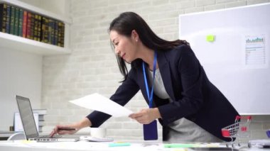 Ofisteki istatistikleri incelerken dizüstü bilgisayarda yazan mutlu Asyalı iş kadını.