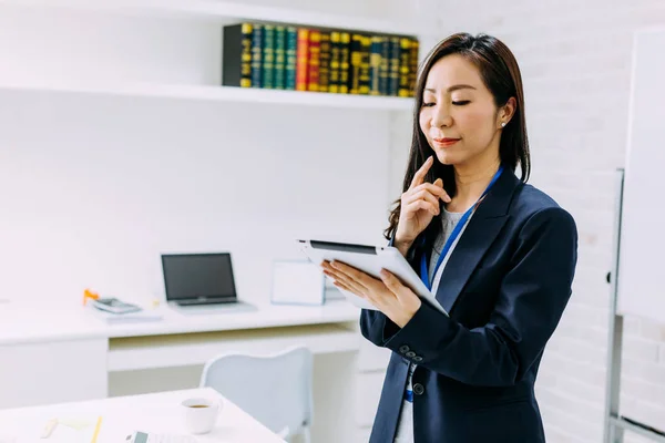 Pensativo asiático mujer de negocios utilizando tableta en la oficina — Foto de Stock