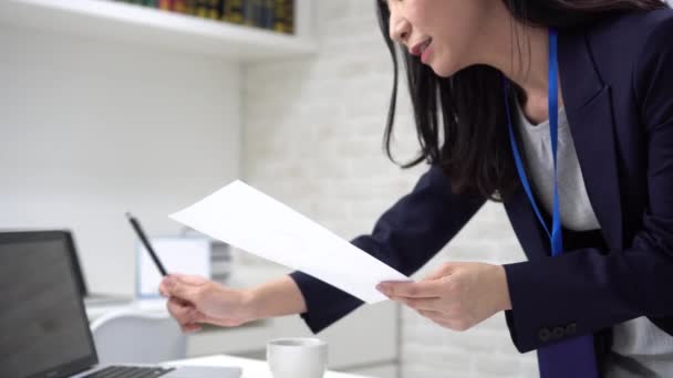 Feliz mujer de negocios asiática escribiendo en el ordenador portátil mientras analiza las estadísticas en la oficina — Vídeos de Stock