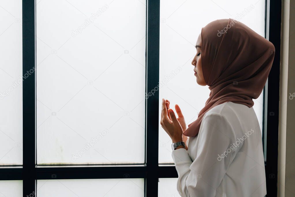 Islamic woman praying near window