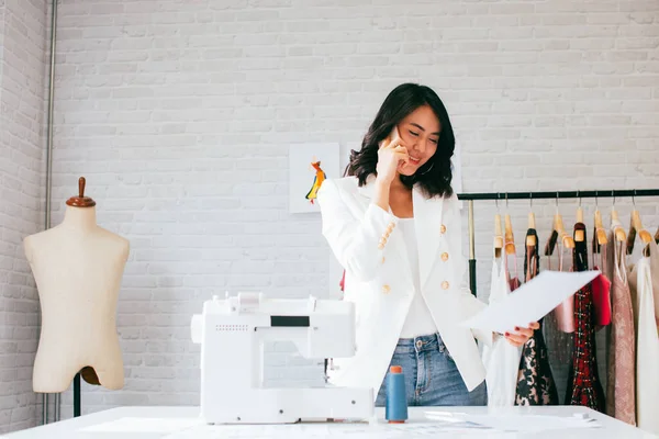 Optimistic Asian female entrepreneur calling on smartphone in studio — Stock Photo, Image