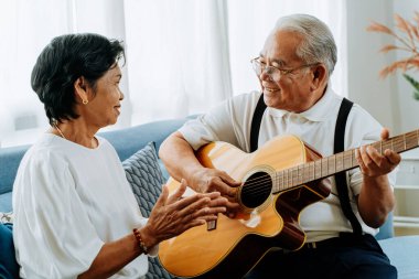 Asyalı son sınıf çifti kanepede oturup akustik gitar çalıyorlar. Mutlu gülümseyen yaşlı kadın, 70 'lerin gitarist kocası şarkı söylerken el çırpıyor. Evde emekliliğin tadını çıkarıyorum..