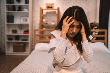Genç, güzel bir Asyalı kadın yatakta yatarken baş ağrısı çekiyor. Evde üzgün ve stresli hissediyor. Hayal kırıklığına uğramış ve çaresiz kız ağlıyor.