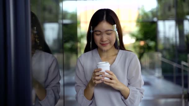Молодая 20-летняя азиатская красивая девушка носит защитный щит для лица и маску. Профессиональная деловая женщина держит чашку кофе - Корона Вирус концепция профилактики — стоковое видео