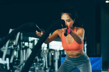 Asyalı kadın vücut geliştirici jimnastik salonunda hareketli çapraz formda halatlar deniyor.