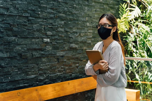 Uma mulher de negócios adulta jovem bem sucedida e feliz segurando um laptop com sorriso. Trabalhadora feminina profissional em pé no escritório moderno corporativo e janela no olhar cinza casual. - Com espaço de cópia — Fotografia de Stock