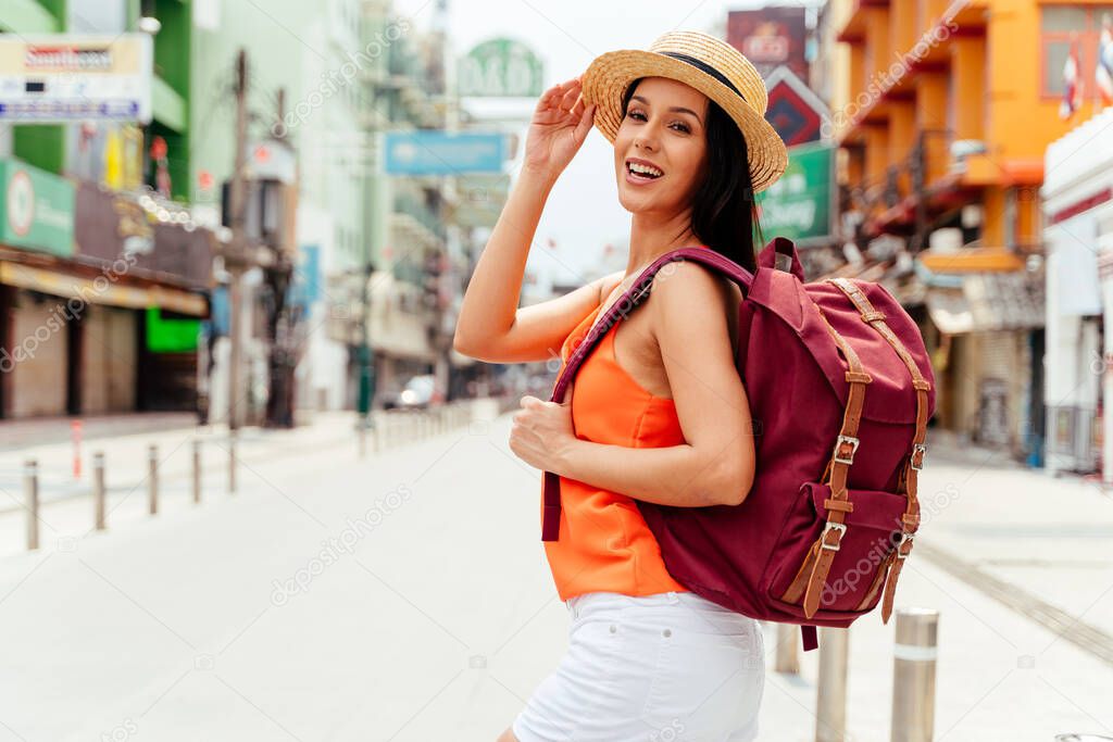Happy and excited Hispanic girl traveler wear summer clothes with hat and backpack bag in Asia.