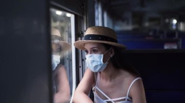 Genç esmer kadın Coronavirus salgını sırasında trenle Tayland 'a gidiyor. 20 'li yaşlarda, Asya' da koruyucu maskeli, yaz kolsuz ve sırt çantalı bir İspanyol kız.