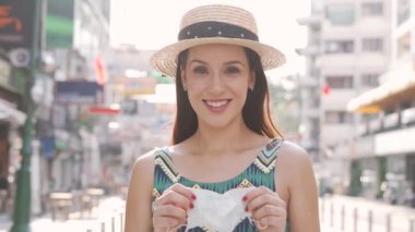 Genç esmer kadın Coronavirus salgını sırasında Tayland, Bangkok 'ta popüler Khao San Yolu' nda seyahat ediyor. 20 'li yaşlarda, Asya' da yaz kolsuz yaz elbisesi giymiş, yüz koruyucu maske takan İspanyol bir kız.